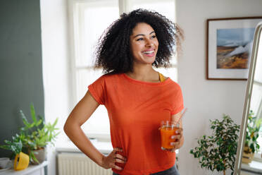 Happy young woman with healthy drink indoors at home, resting after exercise. Sport concept. - HPIF08738