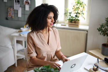 A young woman with laptop indoors at home, home office concept. - HPIF08740