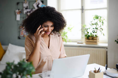 Porträt der jungen Frau mit Laptop und Smartphone drinnen zu Hause, Home-Office-Konzept. - HPIF08743