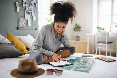 Happy young woman with tablet and map indoors at home, planning traveling trip. - HPIF08754