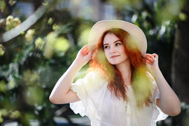 Porträt einer jungen Frau mit Hut, die im Sommer in der Stadt im Freien steht. - HPIF08783