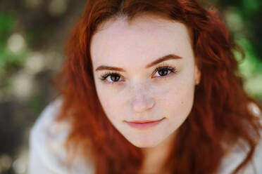 A close-up portrait of young woman outdoors in city, looking at camera. - HPIF08788