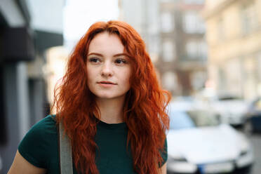 Ein Porträt einer jungen Frau mit Rucksack, die im Freien auf einer Straße steht. - HPIF08797