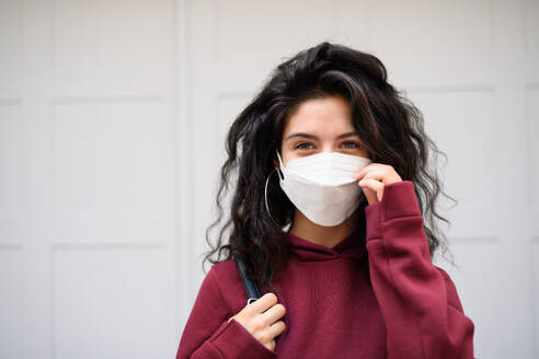 Portrait of happy young woman standing outdoors against white background, looking at camera. Coronavirus concept. - HPIF08801