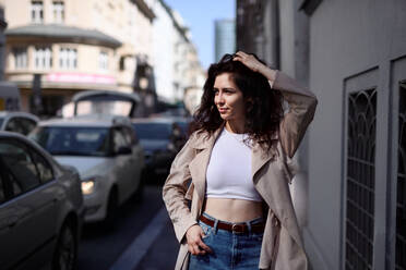 A front view portrait of young woman walking outdoors on street in city. - HPIF08812