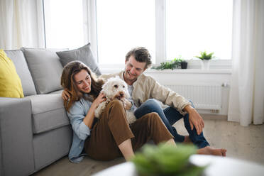 A happy young couple in love with dog indoors at home, resting. - HPIF08824