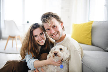 Ein glückliches, verliebtes junges Paar mit Hund in einem Haus, das in die Kamera schaut. - HPIF08827