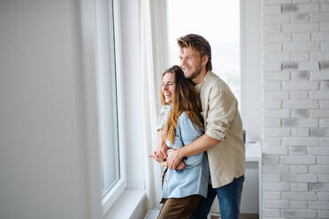 A happy young couple in love indoors at home, hugging and laughing. - HPIF08832