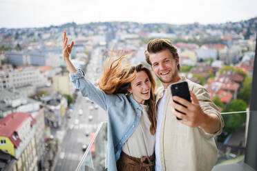 Ein glückliches Paar hält seine Liebe mit der Kamera fest, posiert auf dem Balkon und macht ein Selfie mit seinem Smartphone - HPIF08834