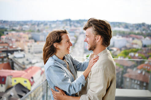 Ein glückliches, verliebtes junges Paar steht auf dem Balkon seines Hauses und sieht sich an. - HPIF08839