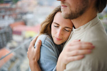 Ein glückliches, verliebtes junges Paar steht im Freien auf dem Balkon seines Hauses und umarmt sich. - HPIF08840