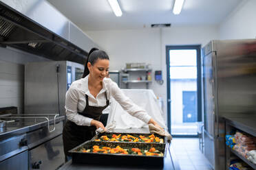 Eine professionelle Köchin bei der Arbeit an ihren Gerichten in einer Restaurantküche. - HPIF08889