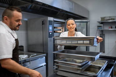 Ein Koch und eine Köchin arbeiten in der Küche eines Restaurants an ihren Gerichten. - HPIF08892