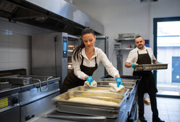 Ein Koch und eine Köchin arbeiten in der Küche eines Restaurants an ihren Gerichten. - HPIF08914
