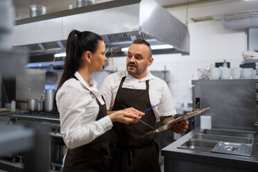 Ein Küchenchef und ein Koch besprechen das Menü in der Küche eines Restaurants. - HPIF08919