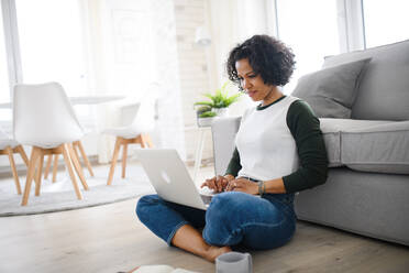 A portrait of happy mature woman working on laptop indoors, home office concept. - HPIF08982