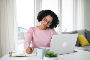 Ein Porträt der glücklichen reifen Frau arbeitet am Laptop drinnen, Home-Office-Konzept. - HPIF08989