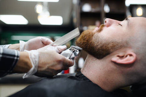 Ein junger Mann besucht einen Friseur in einem Friseursalon, Mittelteil und Nahaufnahme. - HPIF08996