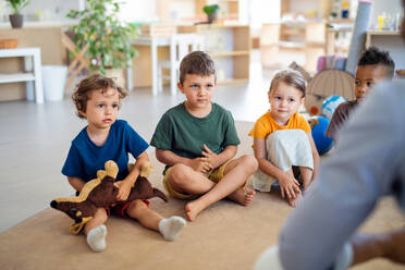 A group of small nursery school children sitting on floor indoors in classroom. - HPIF08998