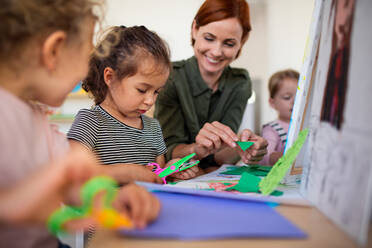 Eine Gruppe von kleinen Kindergartenkindern mit einer Lehrerin in einem Klassenzimmer, Kunst- und Bastelkonzept. - HPIF09041