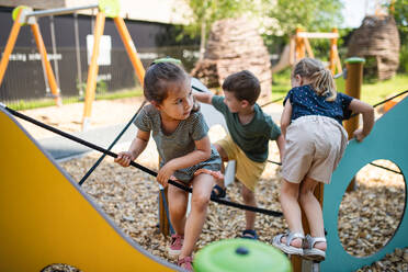 Eine Gruppe von kleinen Kindergartenkindern, die auf einem Spielplatz im Freien spielen. - HPIF09067