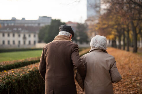 A rear view of senior couple on walk outdoors in park in autumn. - HPIF09127