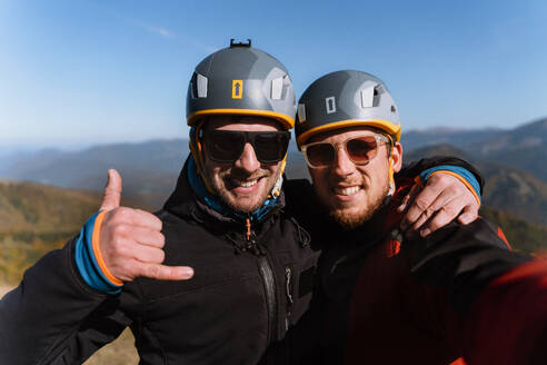 Ein Porträt von zwei Gleitschirmfliegern, die sich auf den Flug in den Bergen vorbereiten und in die Kamera schauen - Extremsport. - HPIF09144