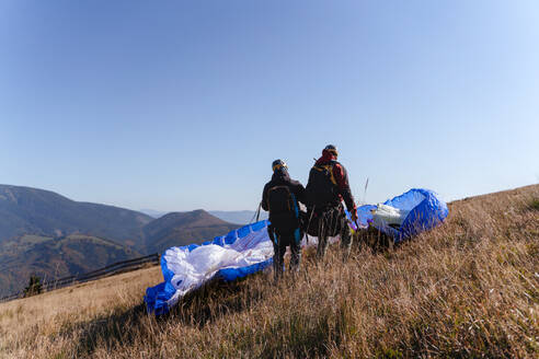 Ein Gleitschirmflieger bereitet sich auf den Flug in den Bergen vor, eine Extremsportart. - HPIF09149