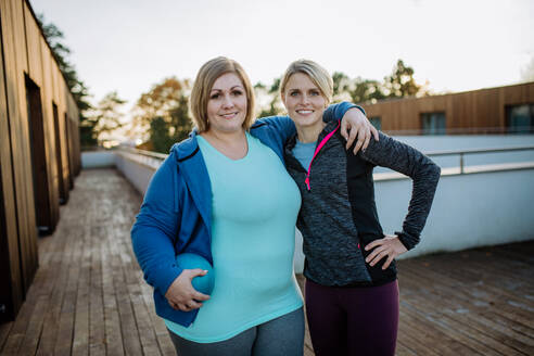 Eine übergewichtige Frau emracing mit Personal Trainer im Freien auf der Terrasse des Fitnessstudios. - HPIF09205