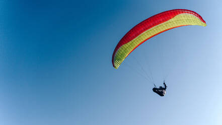 Ein Gleitschirm am blauen Himmel. Der Sportler fliegt mit einem Gleitschirm. - HPIF09219