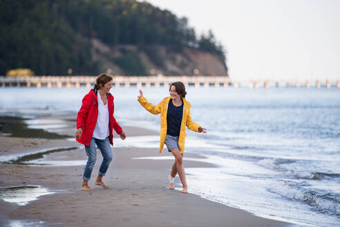 A Senior woman and her preteen granddaughter running and having fun on sandy beach. - HPIF09227