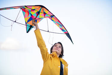 Niedriger Blickwinkel eines glücklichen Mädchens im Teenageralter, das einen Drachen für das Fliegen im Freien vorbereitet. - HPIF09252