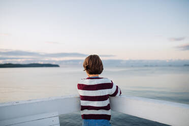A rear view of preteen girl looking at view outdoors on pier by sea, holiday concept. - HPIF09275
