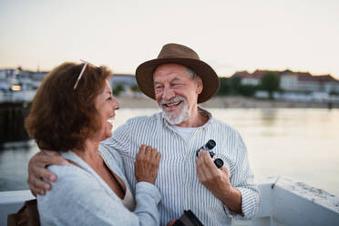 Glückliches, verliebtes älteres Paar, das sich im Freien am Pier am Meer umarmt, sich gegenseitig anschaut und lacht. - HPIF09287
