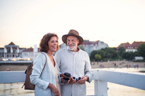 Ein glückliches älteres Paar umarmt sich lächelnd im Freien am Pier am Meer. - HPIF09288