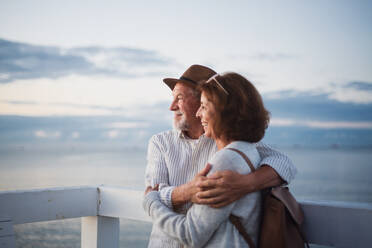 Porträt eines verliebten, glücklichen älteren Paares, das sich im Freien am Pier am Meer umarmt, mit Blick auf die Aussicht, Sommerurlaub. - HPIF09295