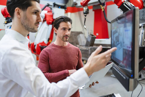 Ingenieure arbeiten gemeinsam am Computerbildschirm in einer Roboterfabrik - DIGF19781