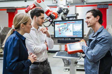 Ingenieur erklärt Kollegen in einer Besprechung in der Roboterfabrik das Steuergerät - DIGF19792