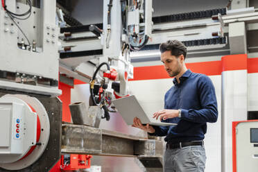 Ingenieur arbeitet am Laptop in der Roboterfabrik - DIGF19832