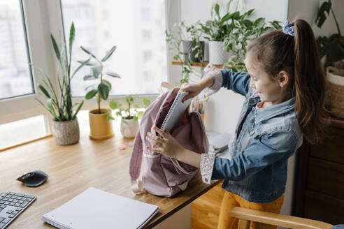 Mädchen nimmt zu Hause Bücher aus dem Rucksack - SSYF00092