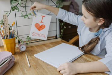 Girl pinning card on wire rack at table at home - SSYF00103