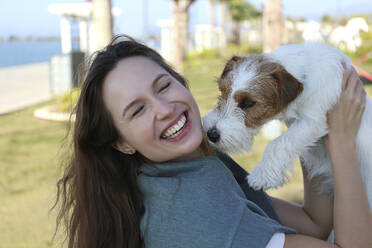 Happy woman having fun with dog in park - SYEF00240