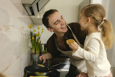 Vater und Tochter backen Pfannkuchen zum Frühstück zu Hause - VIVF00416