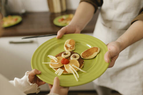 Father and daughter holding cute Easter bunny shape pancake at home - VIVF00423