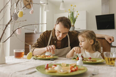Father and daughter eating pancakes for breakfast at home - VIVF00433