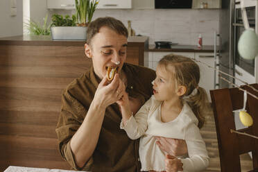 Tochter füttert den Vater zu Hause mit Pfannkuchen - VIVF00439