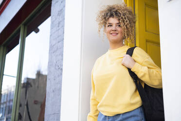 Contemplative woman with backpack standing at doorway - AMWF01188