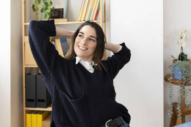Happy businesswoman with hands behind head in office - XLGF03267