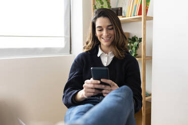 Smiling businesswoman using smart phone in office - XLGF03268