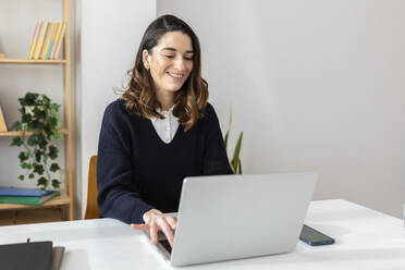 Smiling businesswoman working on laptop at office - XLGF03275